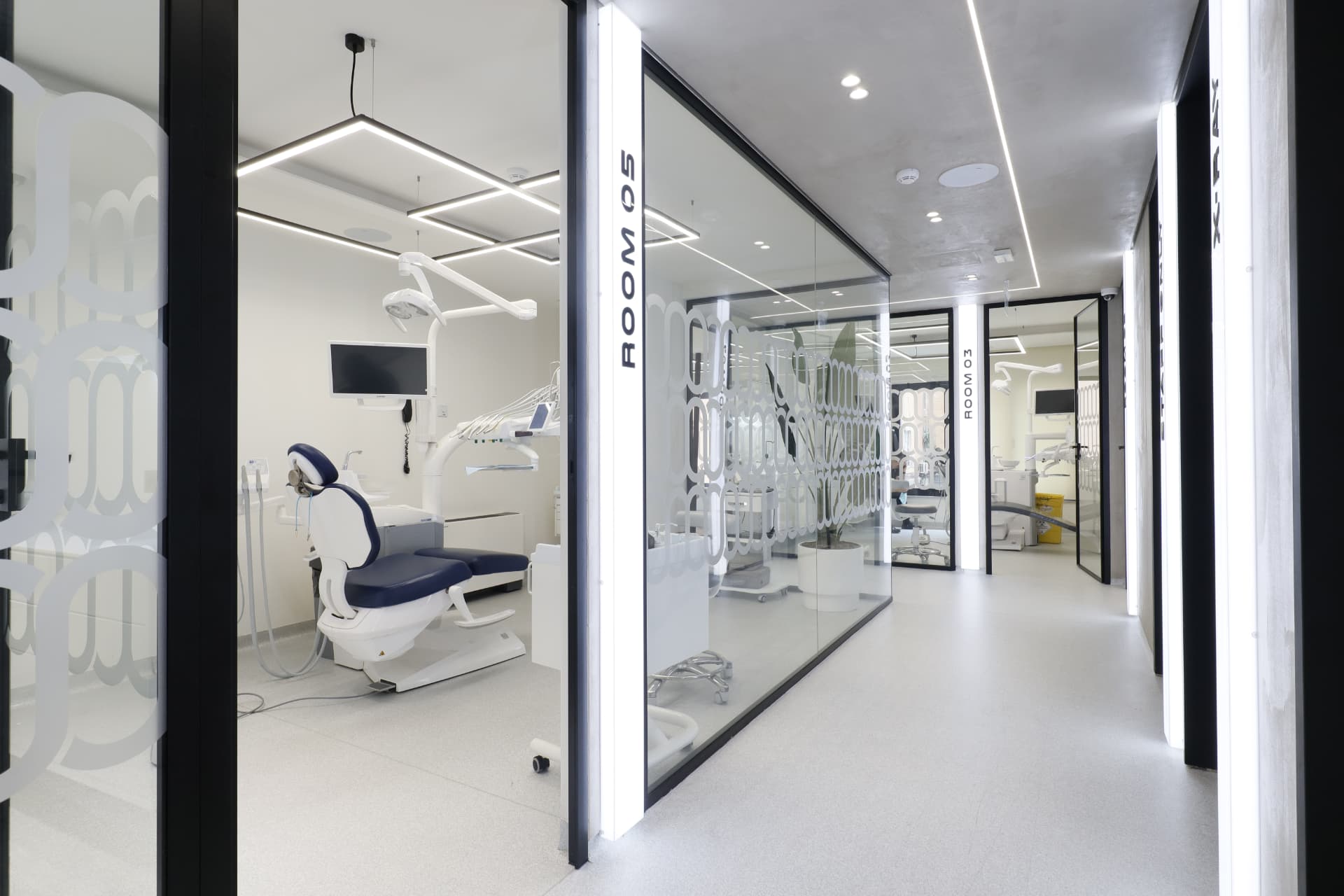 Modern dental clinic in Albania — glass-walled treatment rooms with advanced dental chairs and LED lighting